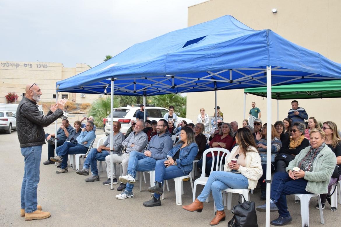 האורחים יושבים מתחת לגזיבו ומקשיבים למילות ראש המועצה