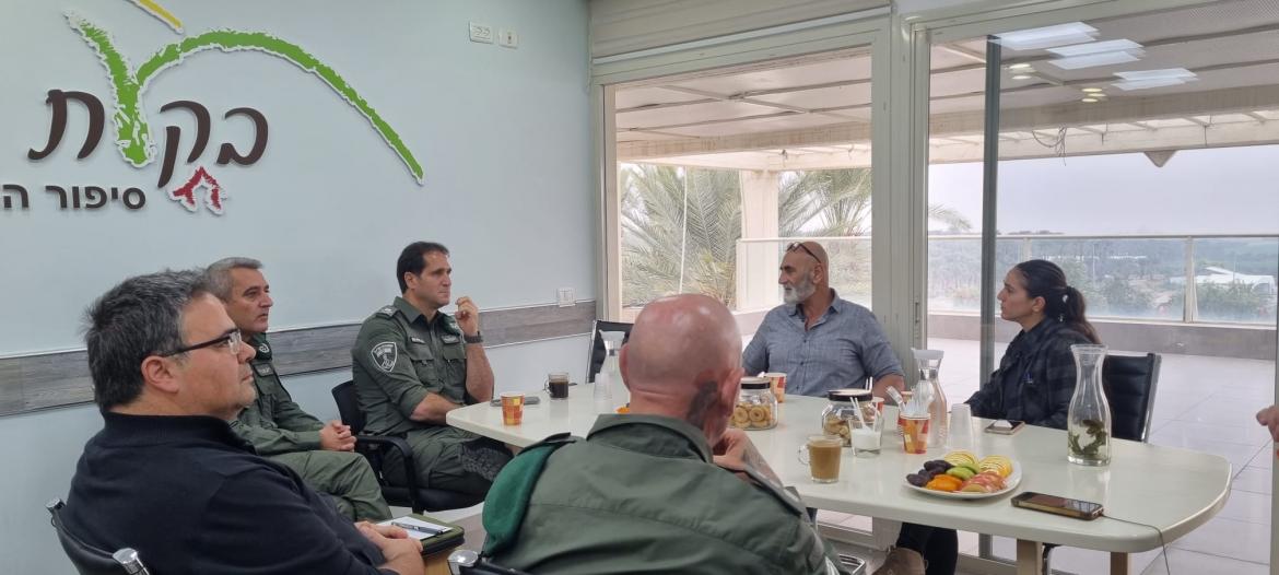 פגישת עבודה עם מפקד מגב, ראש המועצה, קבט המועצה וקצינים בכירים היושבים ליד שולחן עם כיבוד קל