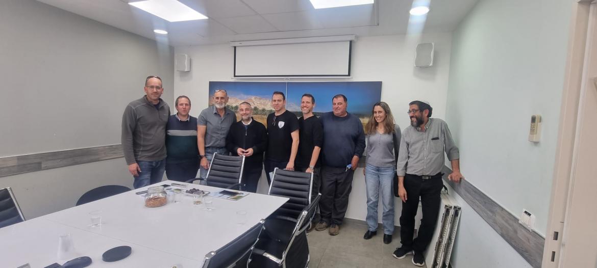 סגן השר, ראש המועצה, חברי מליאה ועובדי מועצה עומדים בחדר ישיבות ליד שולחן וכסאות