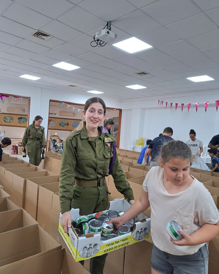 חיילת וילדה מחזיקים מצרכים כדי להכניס אותם לארגזים