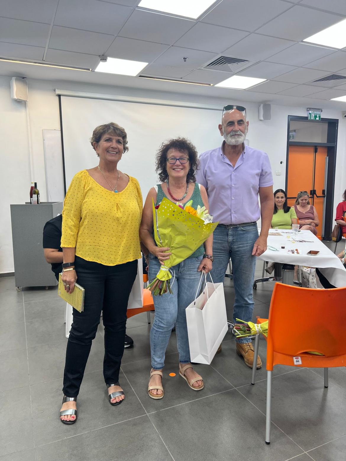 ראש המועצה, מזכיר המועצה והפורשת לילי בן עמי באמצע מחזיקה זר פרחים