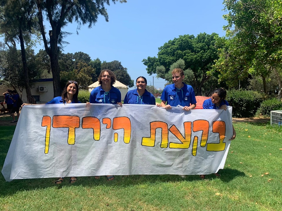 חברי גרעין הנוער עומדים עם שלט "בקעת הירדן" בחצר בית הספר