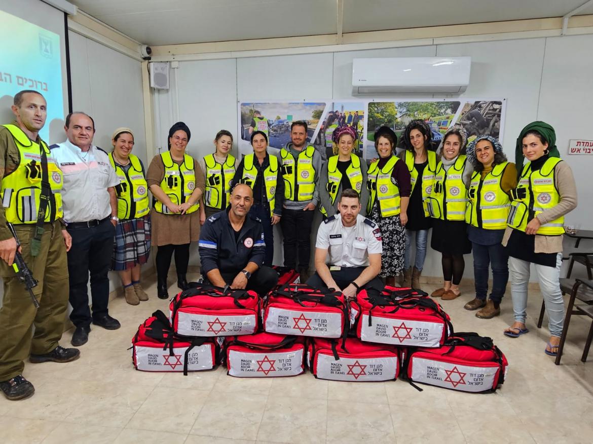 משתתפי ההדרכה עם עומדים עם וסטים של רפואה ואנשי מד"א  לידם. לפניהם תיקי רפואה